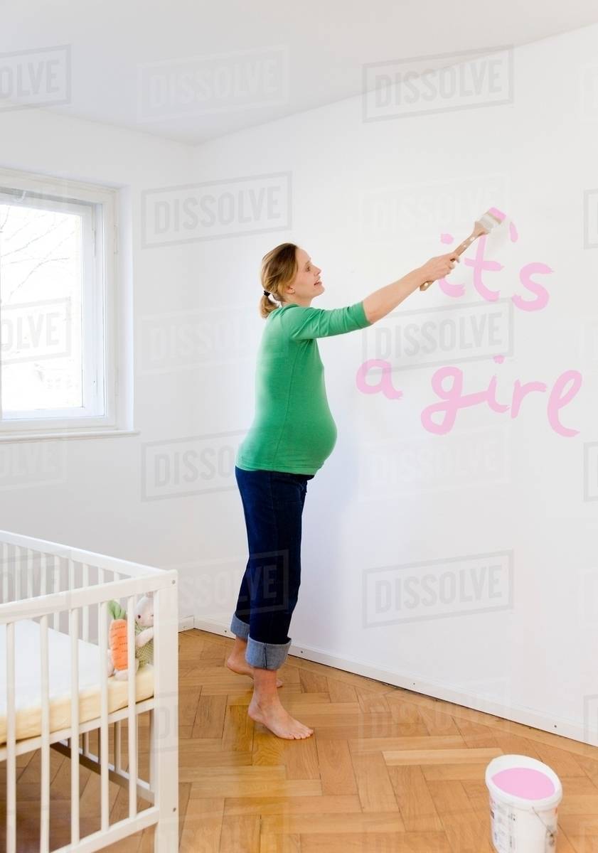 Pregnant woman painting nursery Stock Photo Dissolve