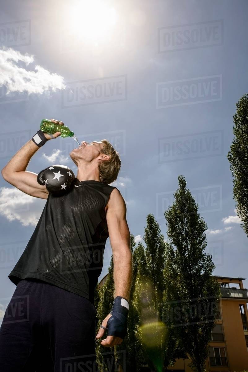 Mid adult male boxer drinking bottled water in park Stock Photo