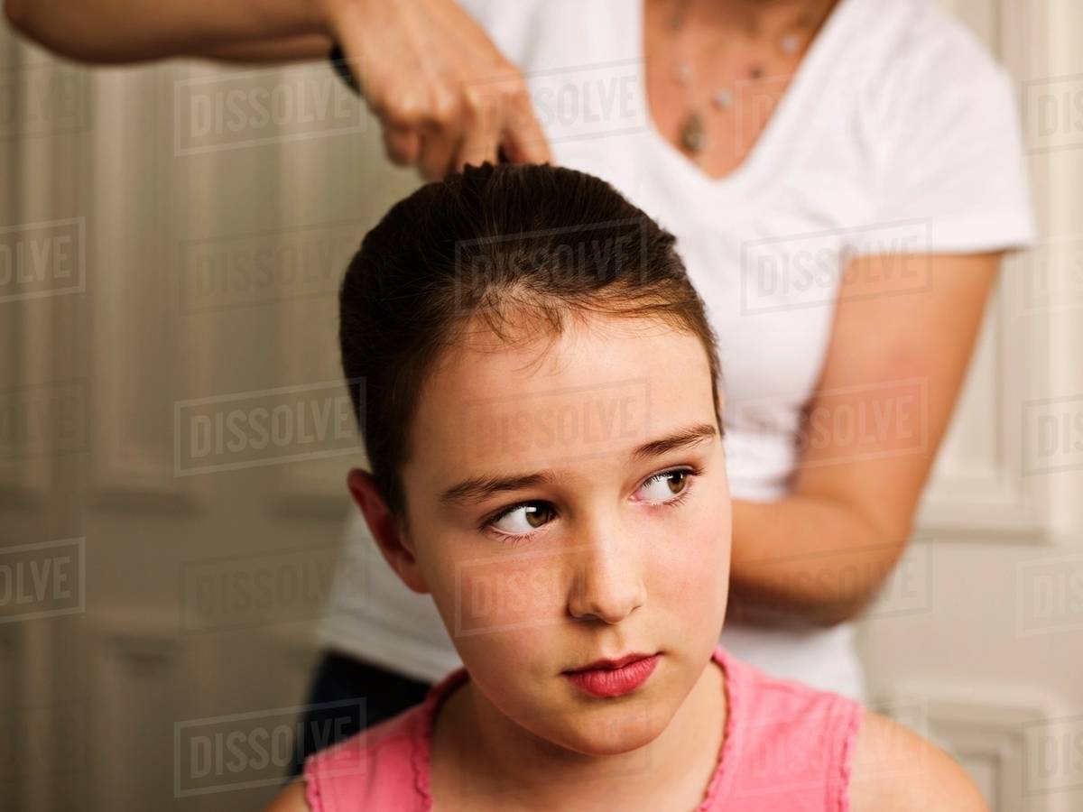 A Woman Tying A Girls Hair Back Stock Photo Dissolve