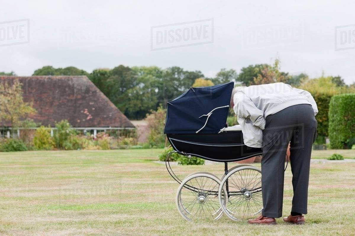 Grandfather looking at baby in pram Stock Photo Dissolve