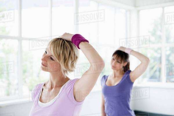 Two women stretching neck - Stock Photo - Dissolve