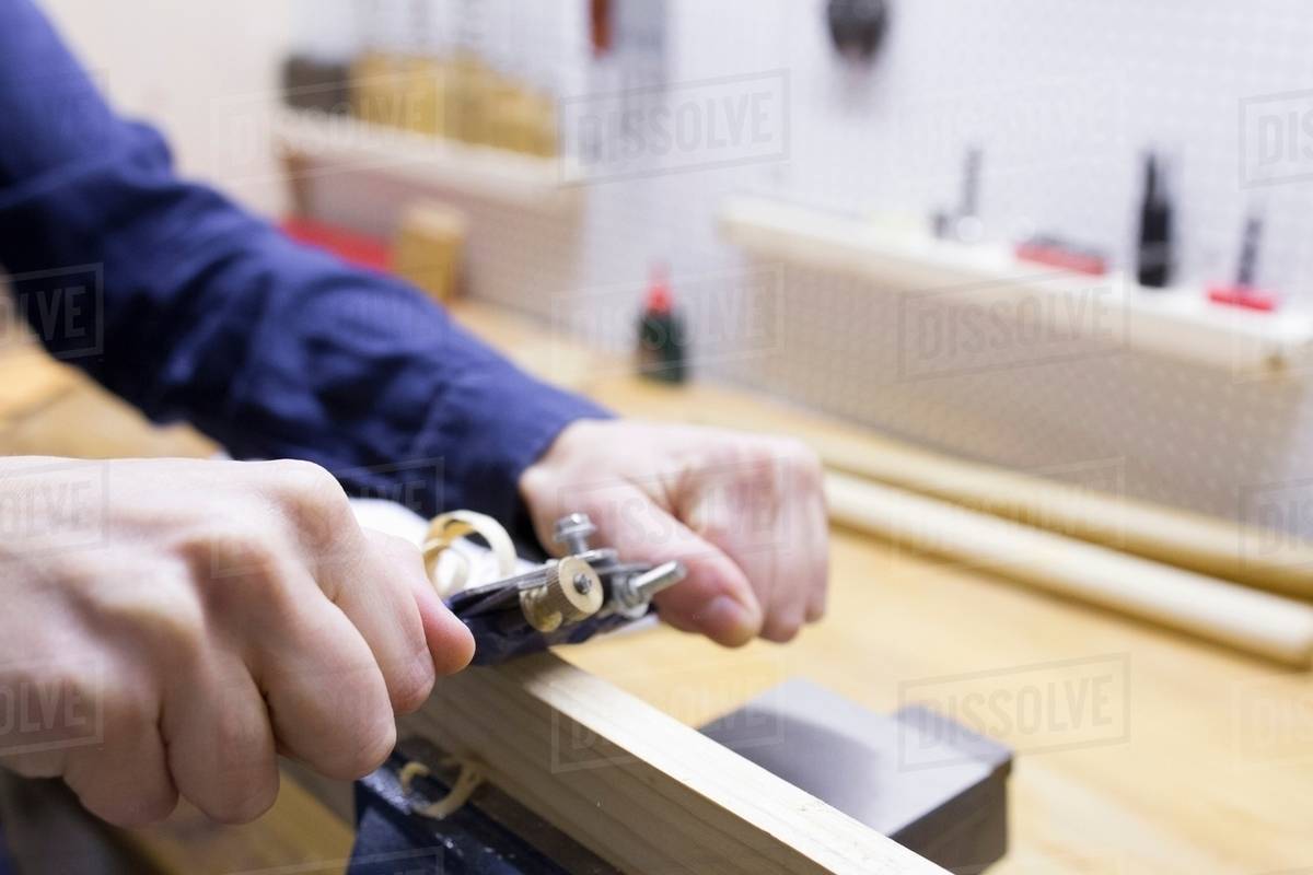 Close up of young female carpenters hands planing timber in