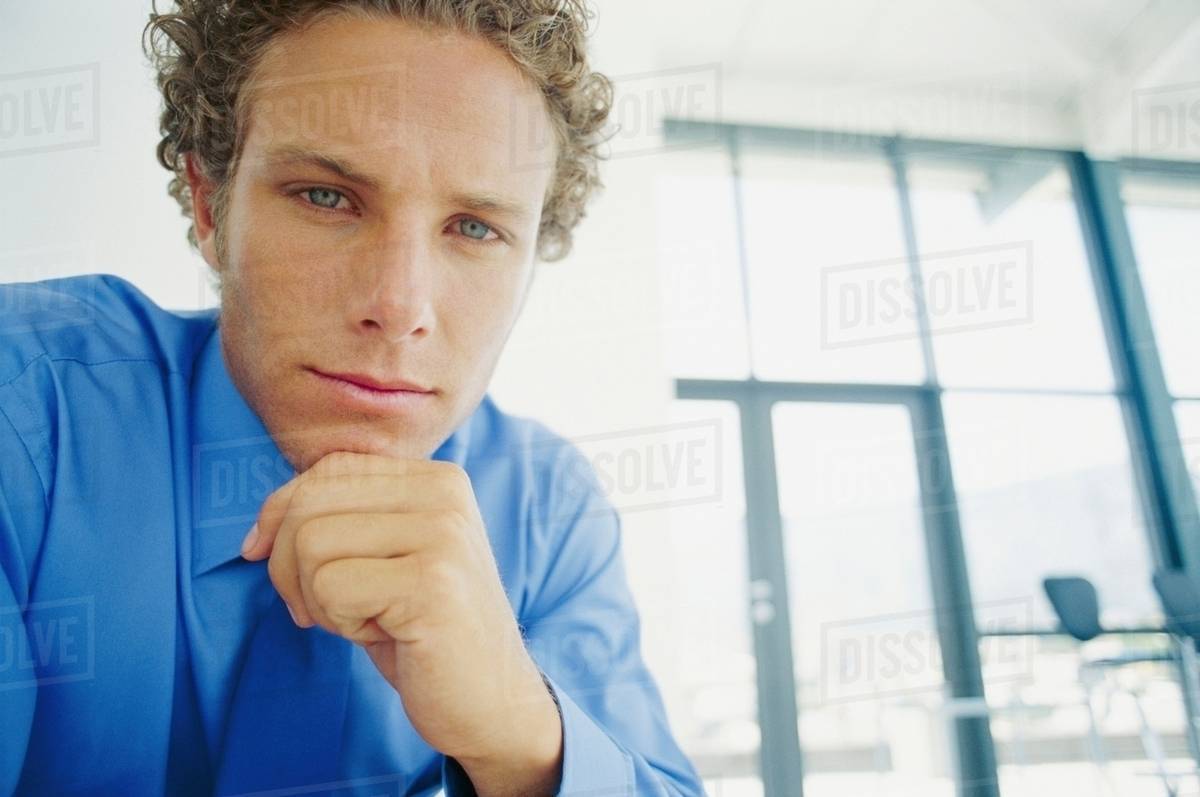 Businessman holding chin in hand Stock Photo Dissolve