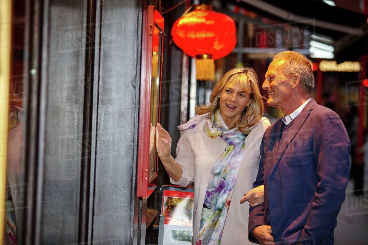 Mature dating couple reading restaurant menu in China Town, London, UK ...