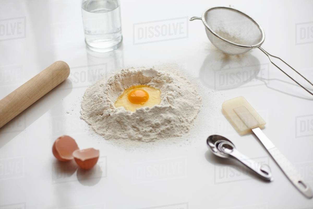 Baking preparation with raw egg in center of flour stack and kitchen ...
