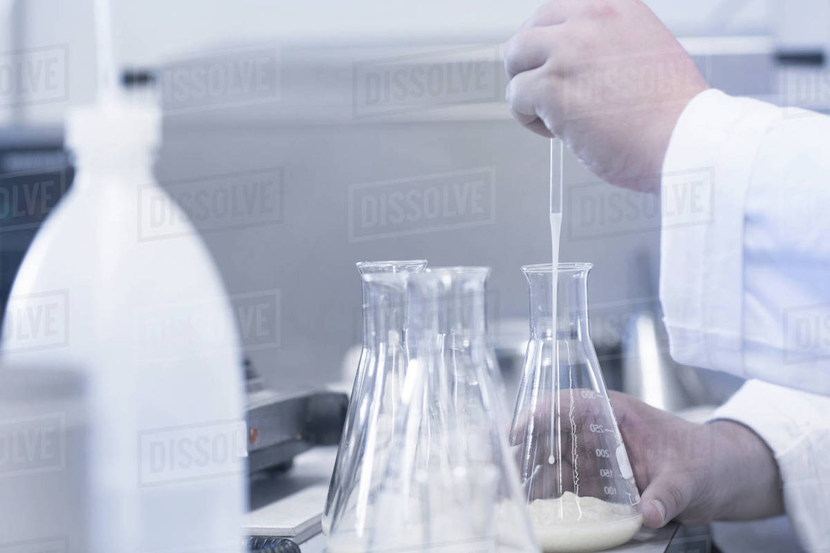 Scientist pipetting sample into beaker in laboratory Stock Photo