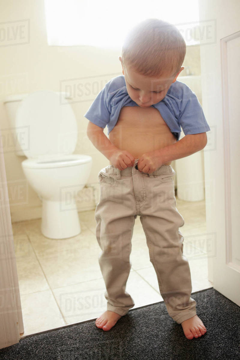 Boy buttoning his pants in bathroom Stock Photo Dissolve