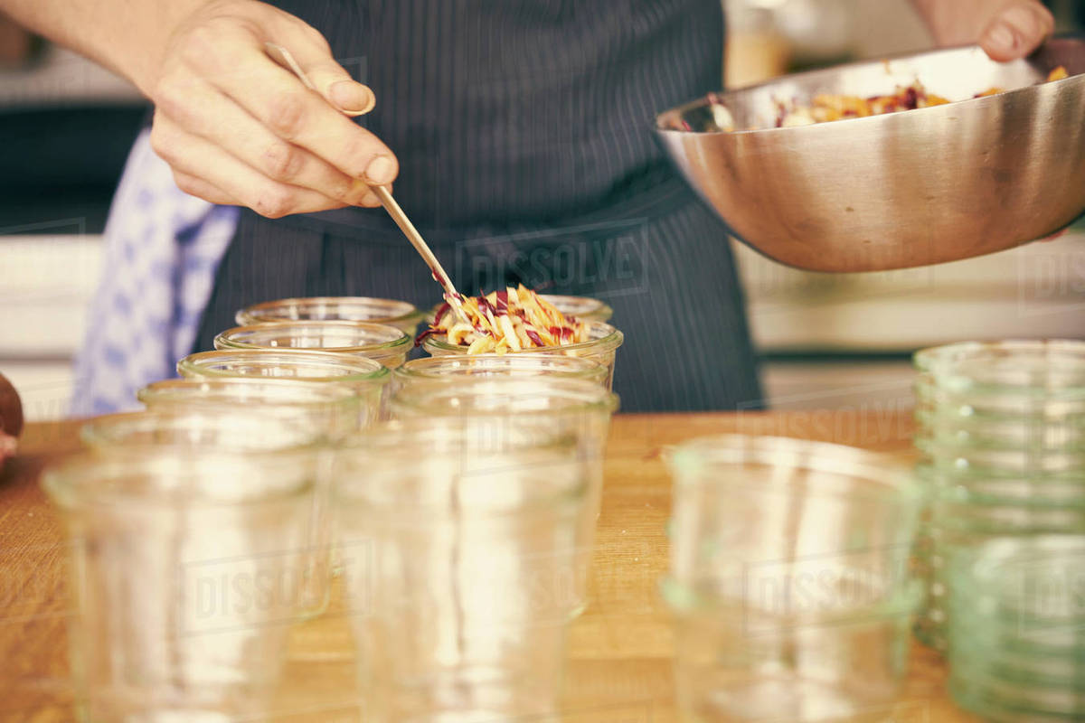 Chef filling plastic containers with portions of food Stock Photo