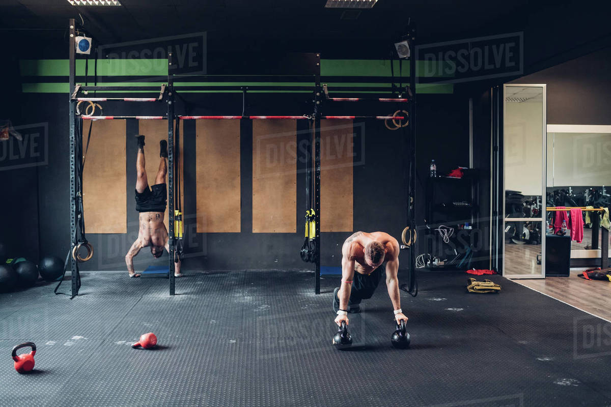 Young men training in gym, doing push ups and handstand Stock Photo Dissolve