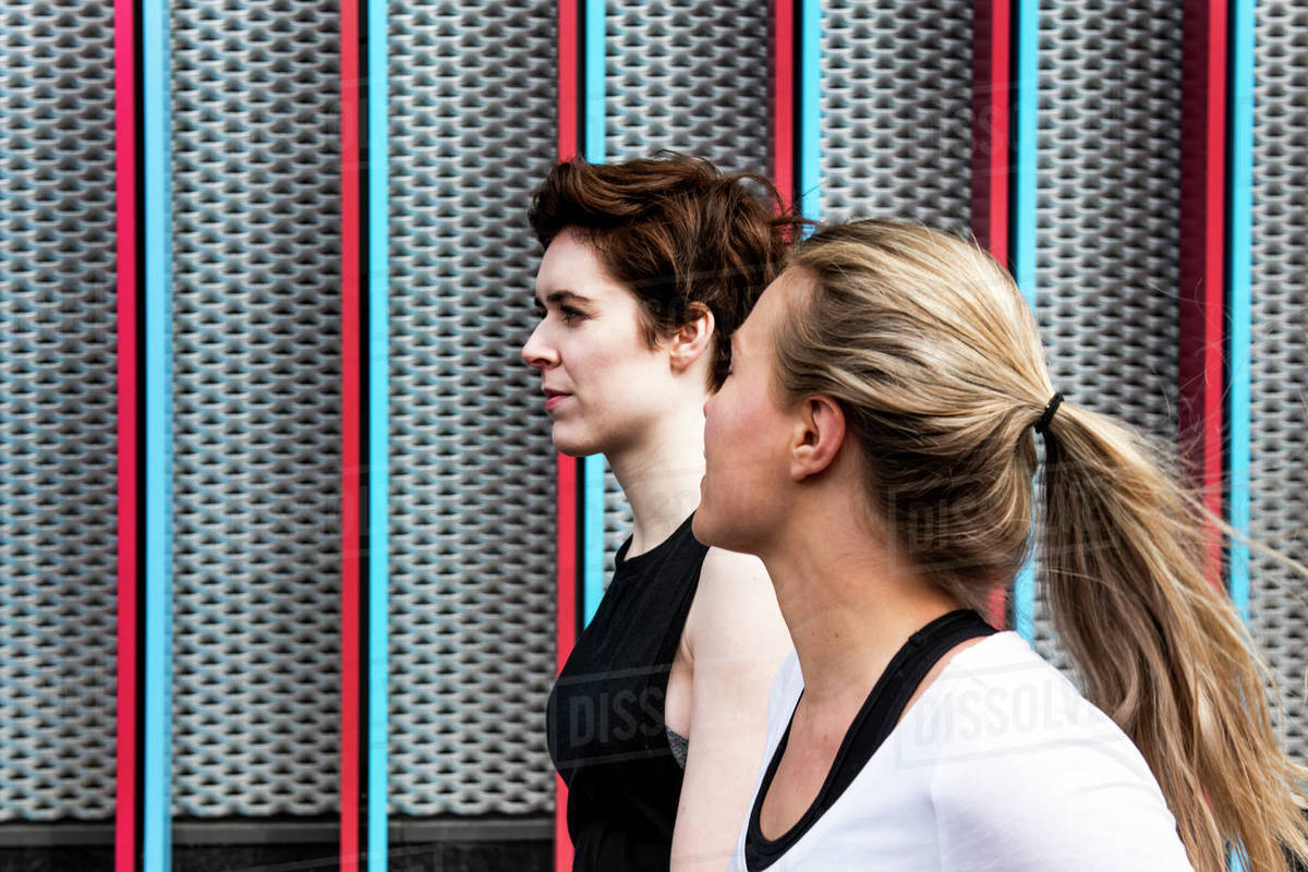 Two young female runners talking on city sidewalk, head and shoulders Royalty-free stock photo