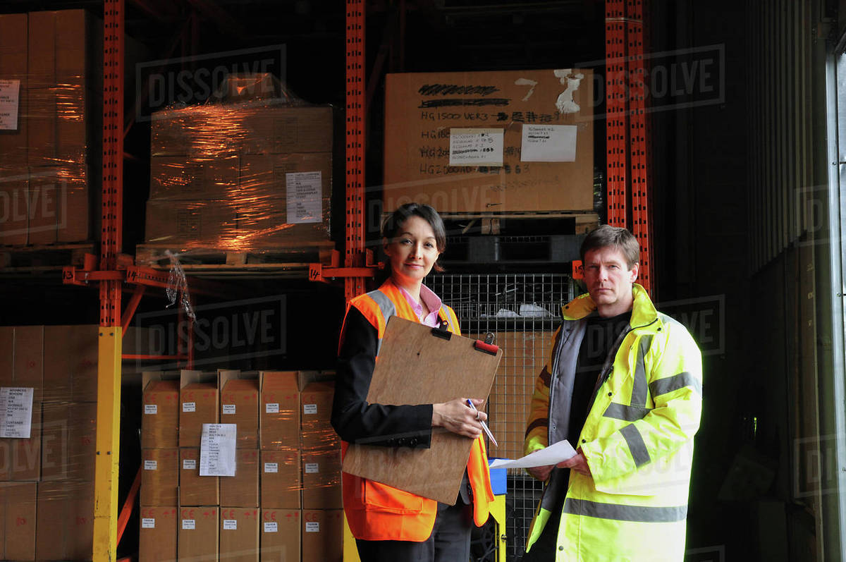 Male and female factory workers with clipboard in warehouse, portrait Royalty-free stock photo