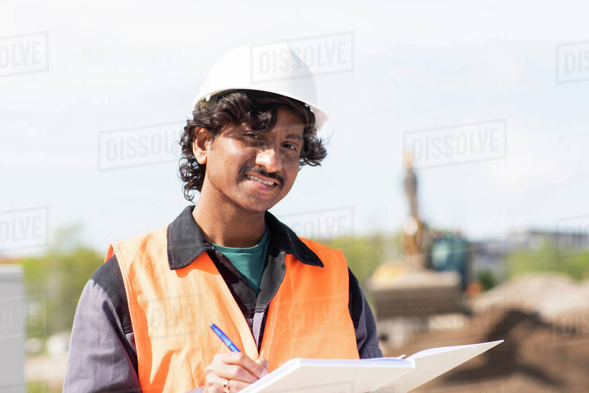 Male engineer on construction site writing in notebook, head and shoulder portrait Royalty-free stock photo