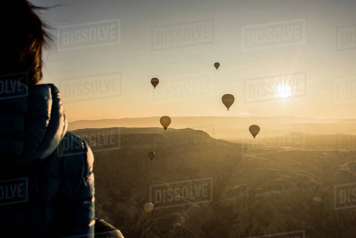 Woman enjoying view, hot air balloons flying in background, Göreme, Cappadocia, Nevsehir, Turkey  Royalty-free stock photo