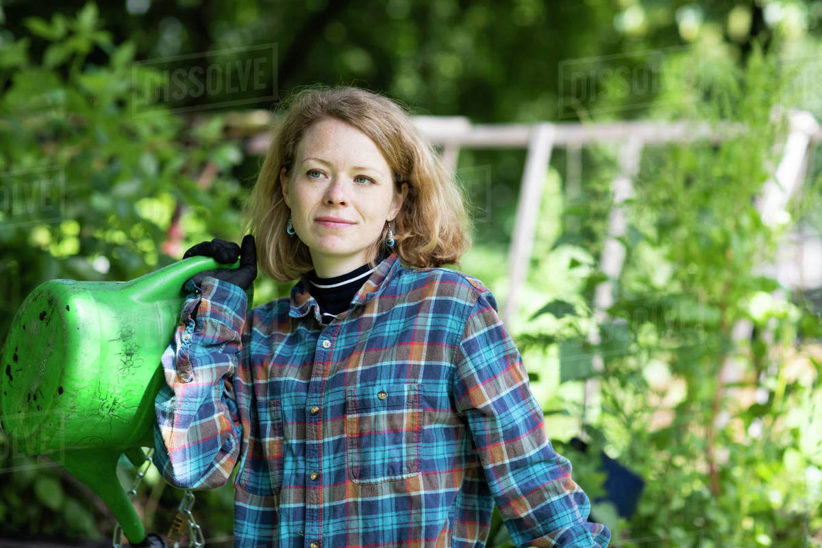 Mid adult woman carrying watering can in her garden Royalty-free stock photo