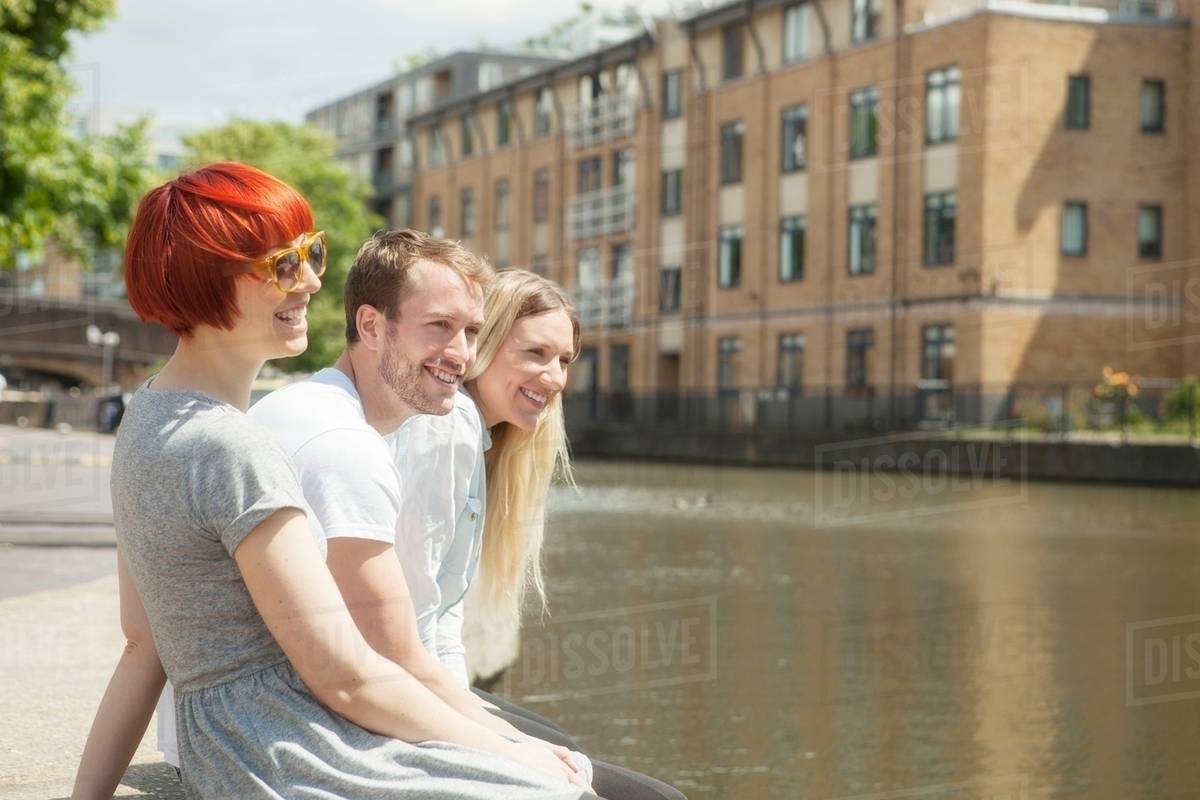Friends sitting on canal side, East London, UK Stock Photo Dissolve