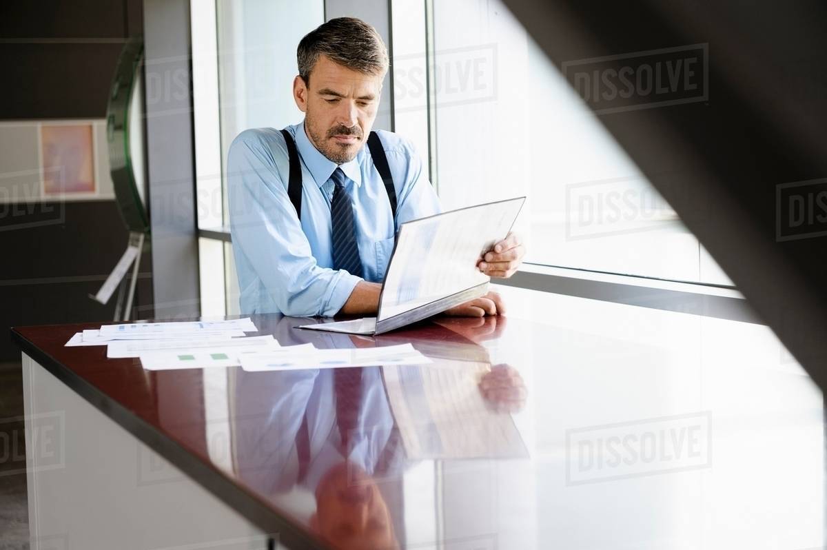 Businessman reading at desk Stock Photo Dissolve