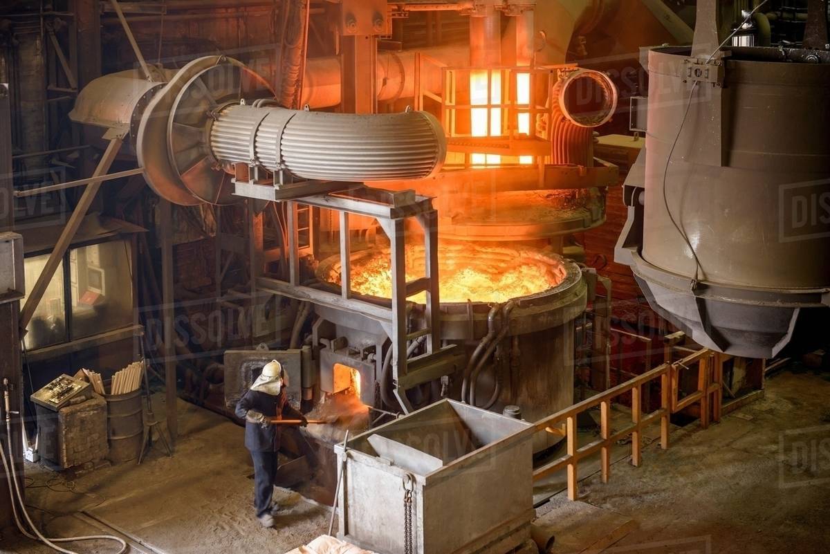 Steel worker working at an open electric steel furnace in an industrial