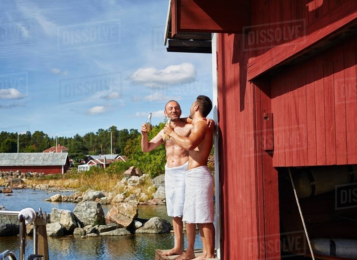 Two men with beers outside sauna Stock Photo Dissolve