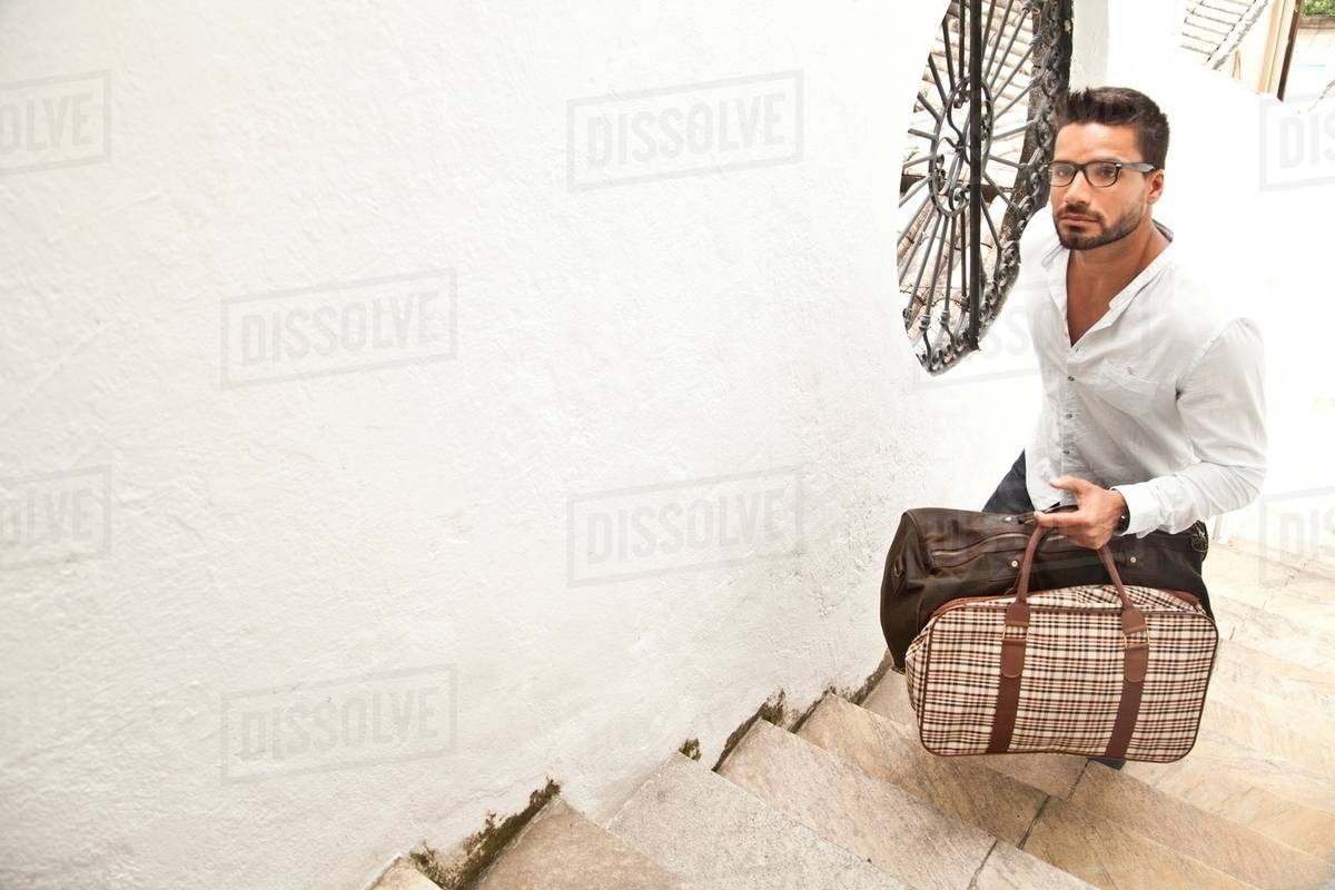 Man going up stairs with luggage Stock Photo Dissolve