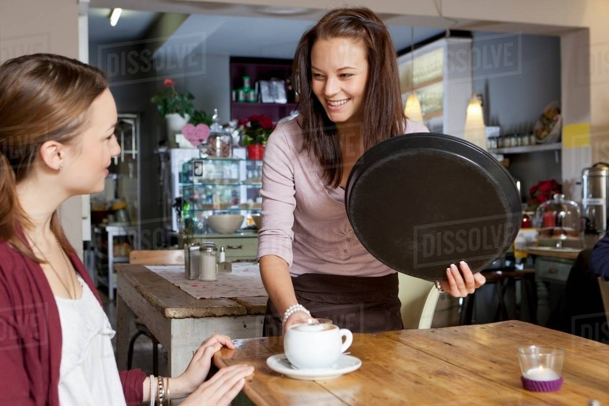 Waitress serving woman in cafe Stock Photo Dissolve