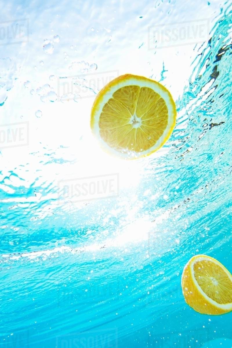 Lemons floating in swimming pool Stock Photo Dissolve