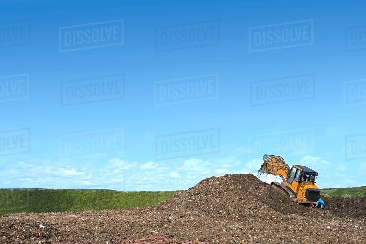 Digger on mound burying waste on landfill site Stock Photo Dissolve