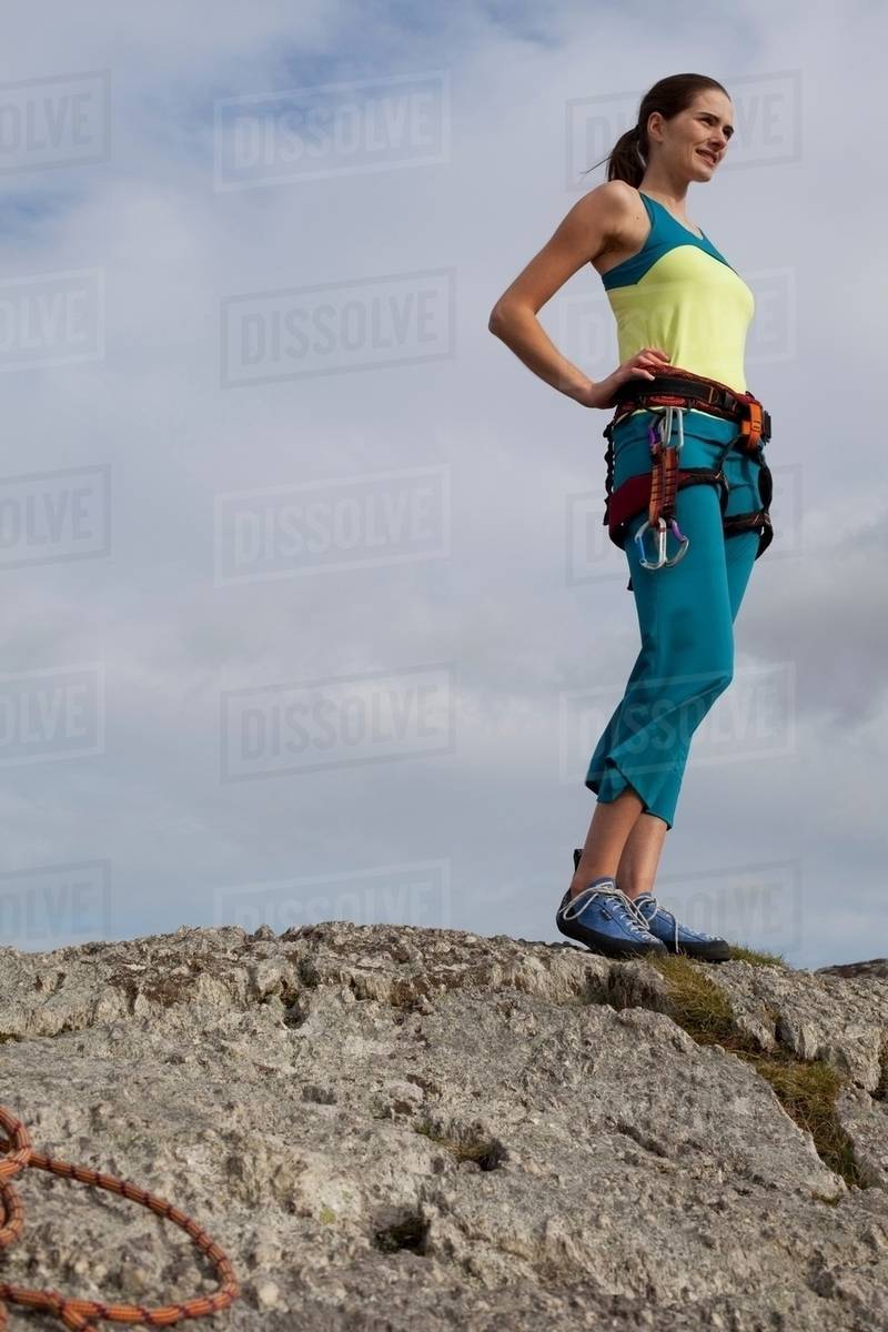 Woman in climbing gear on top of rock Stock Photo Dissolve