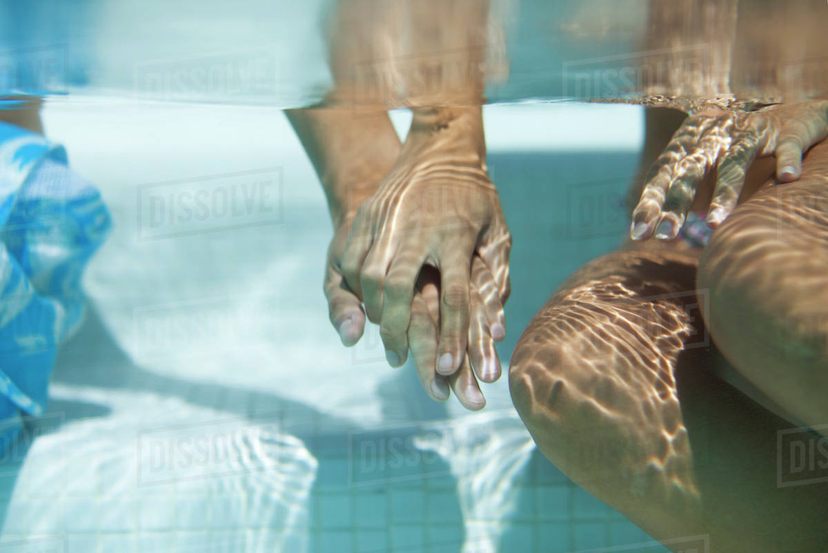 Couple holding hands underwater, cropped Stock Photo Dissolve