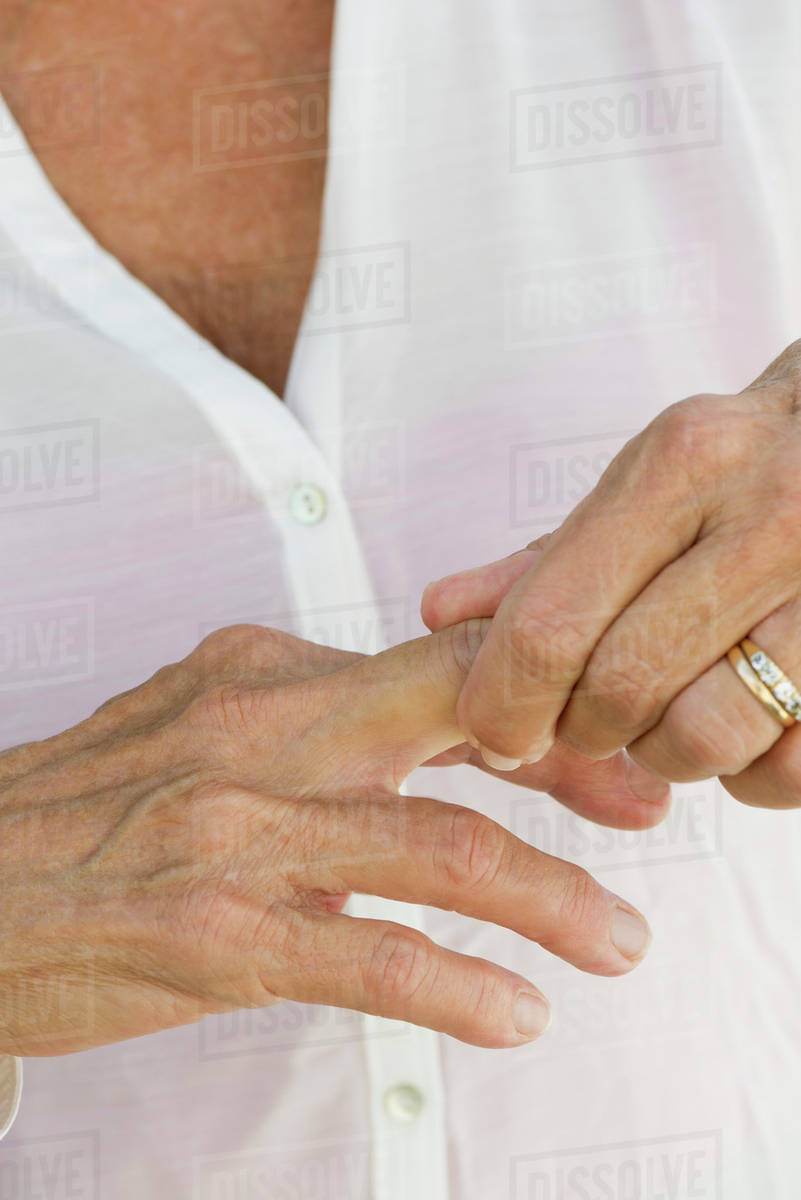 Senior woman rubbing knuckles, cropped Stock Photo Dissolve