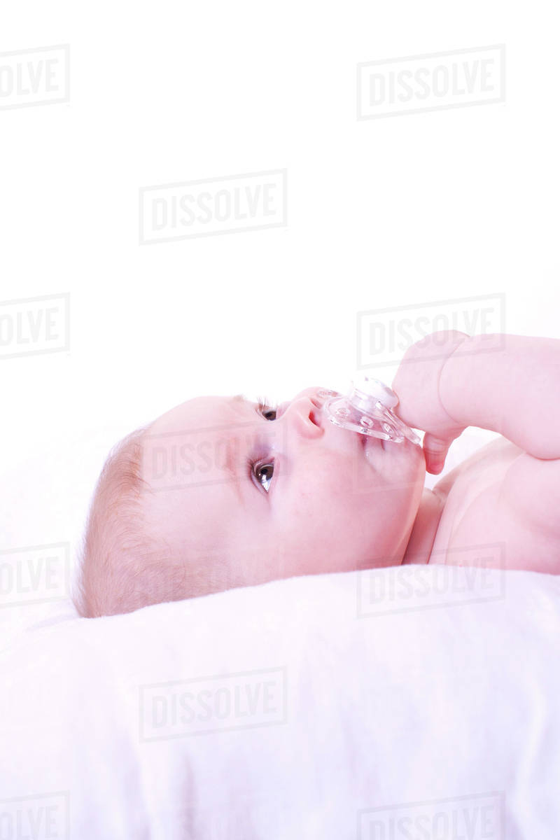 Baby lying down with pacifier in mouth Stock Photo Dissolve