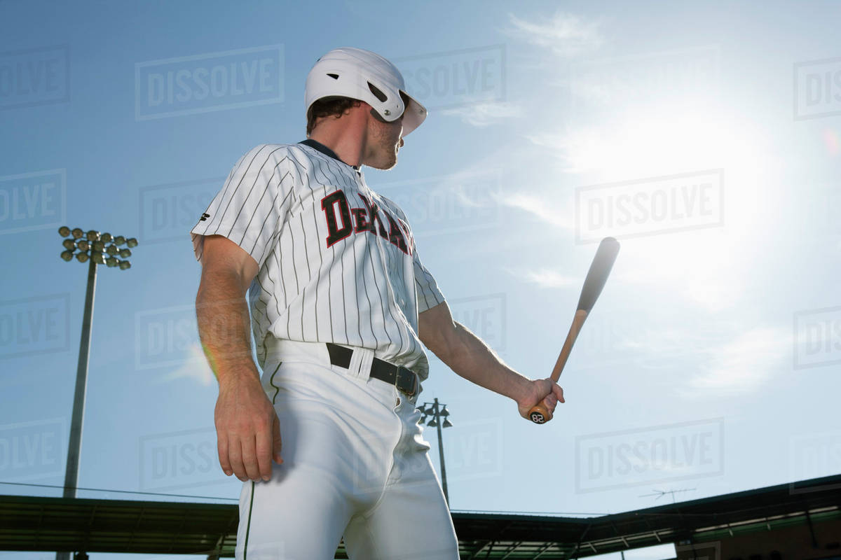 Baseball player holding bat, looking over shoulder Stock Photo Dissolve