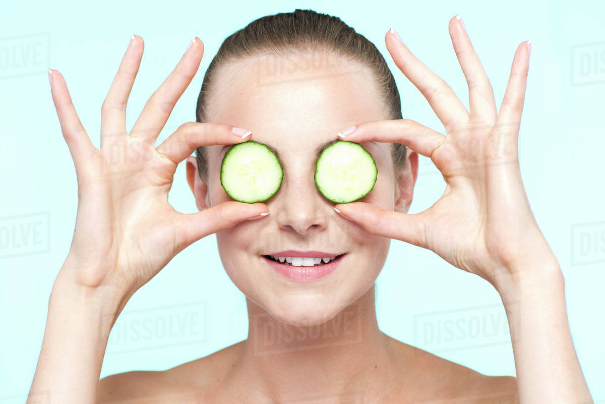 Woman holding cucumber slices on eyes Stock Photo Dissolve