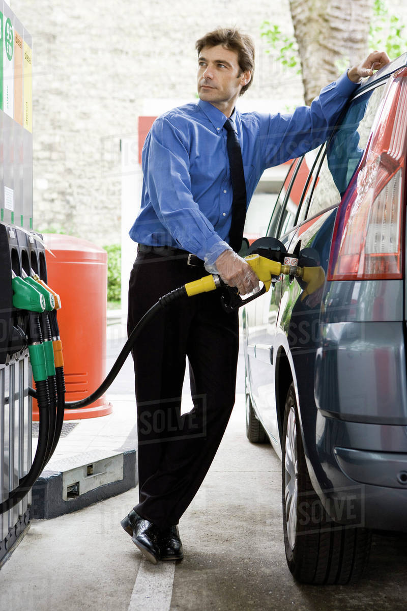 Welldressed man refueling vehicle at gas station Stock Photo Dissolve