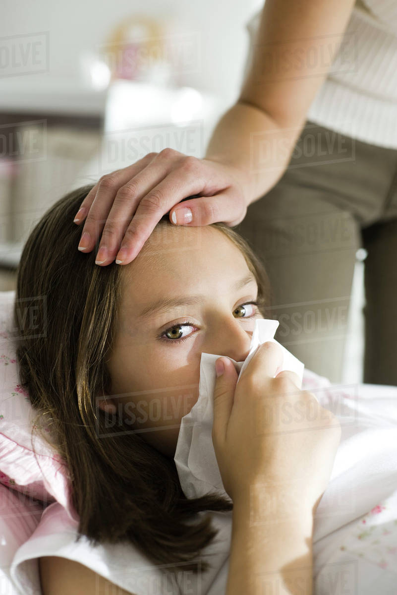 Girl with head cold, mother caressing forehead Stock Photo Dissolve