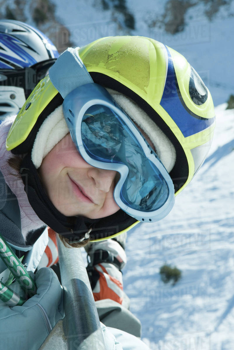 Girl wearing ski goggles and helmet, smiling at camera, portrait