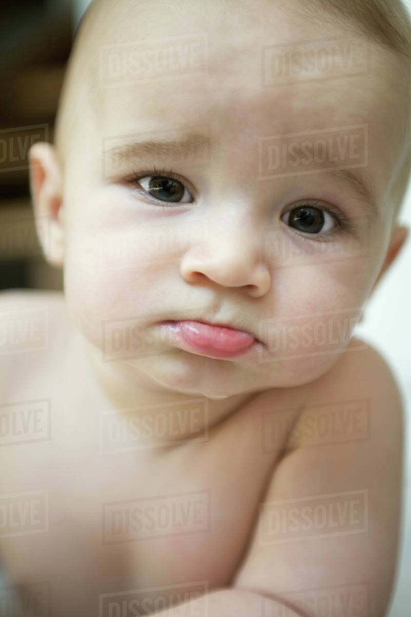 Baby sticking out lower lip and furrowing brow, looking at camera