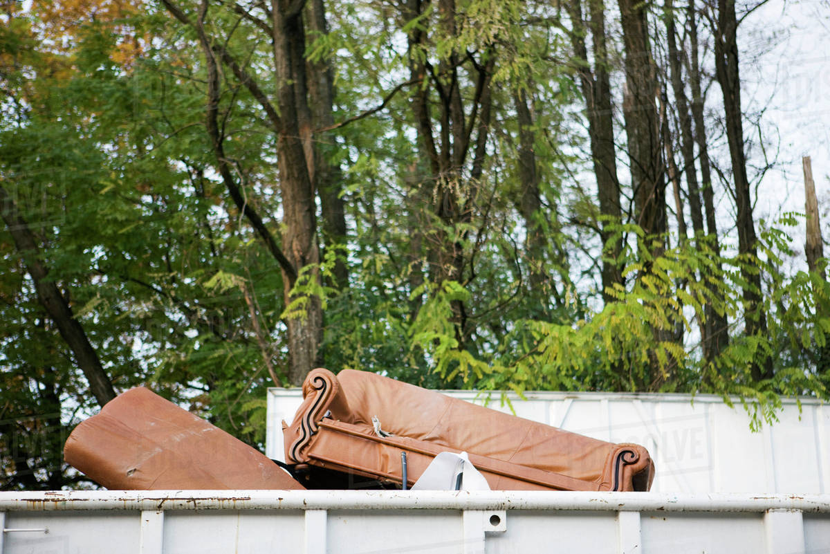 Sofa sticking out of top of dumpster Stock Photo Dissolve