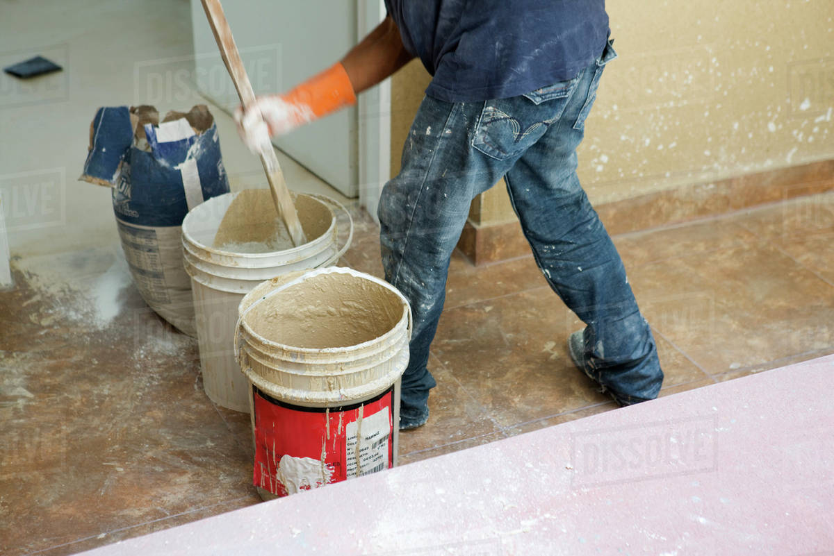 Worker mixing plaster in bucket Stock Photo Dissolve