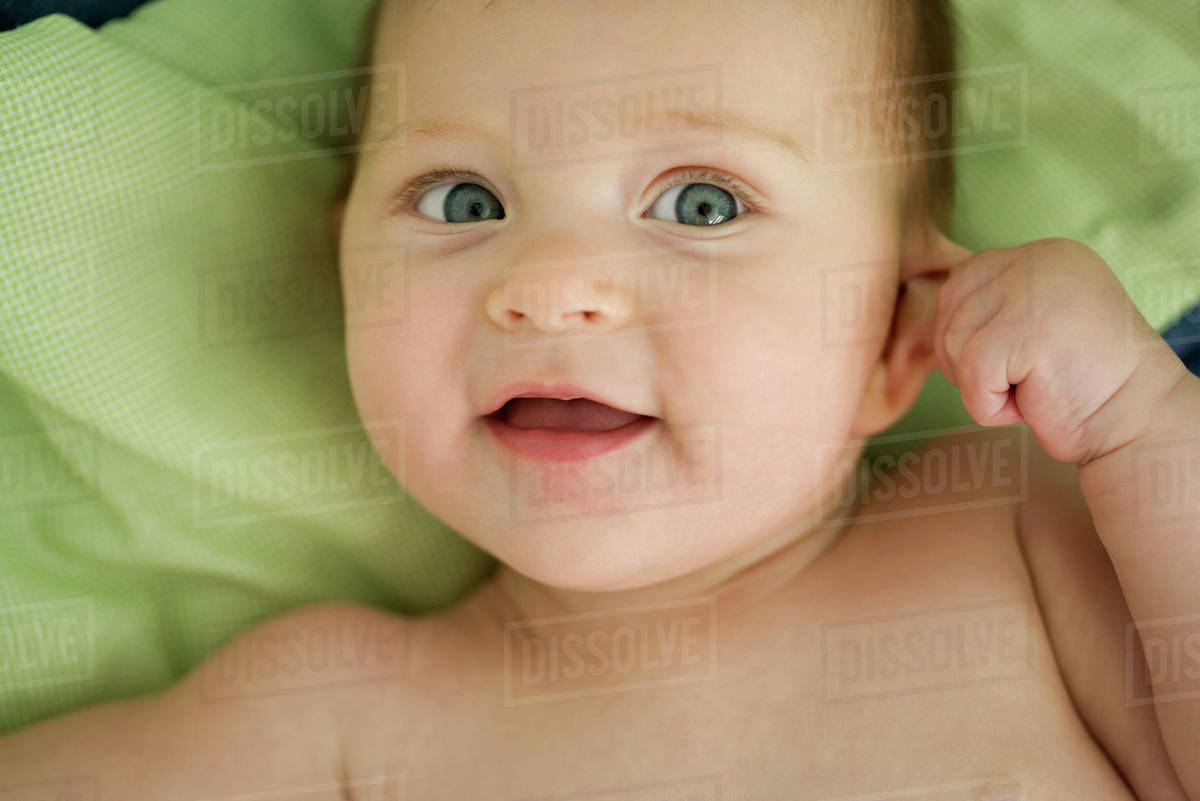 Baby pulling on ear, smiling Stock Photo Dissolve