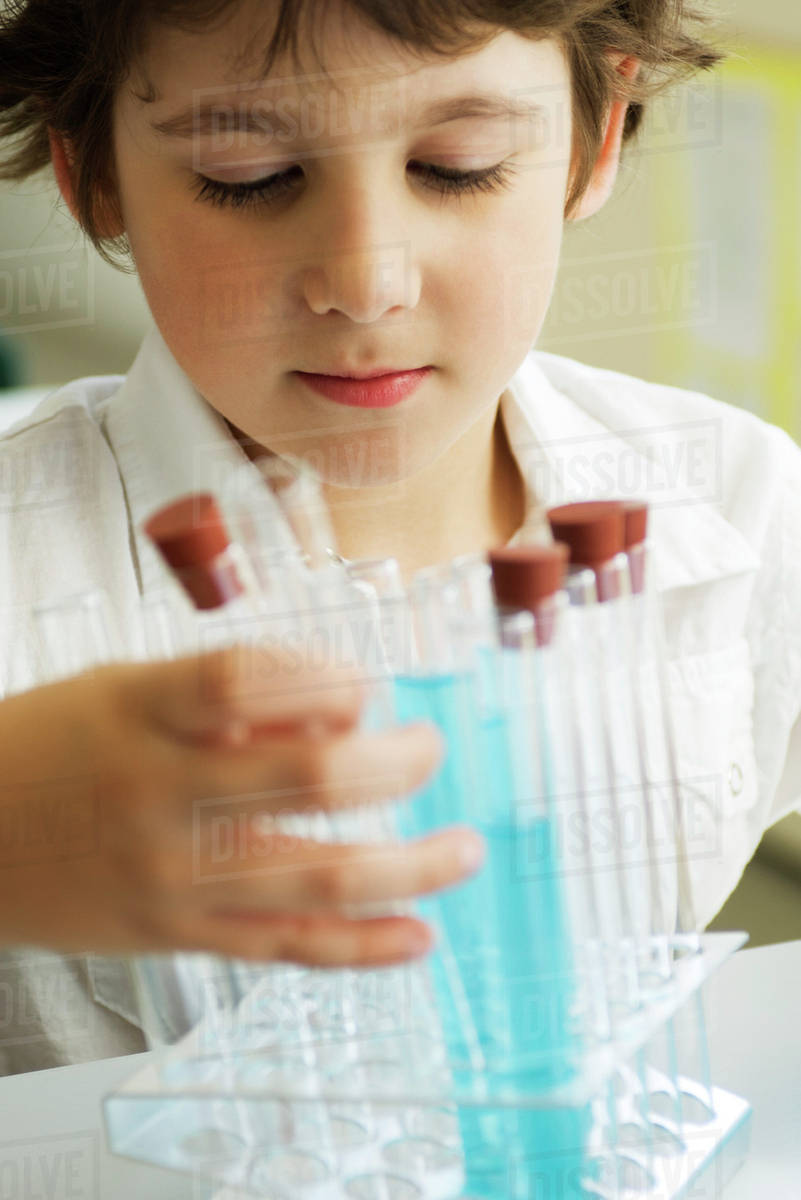 Boy placing test tubes in test tube rack Stock Photo Dissolve