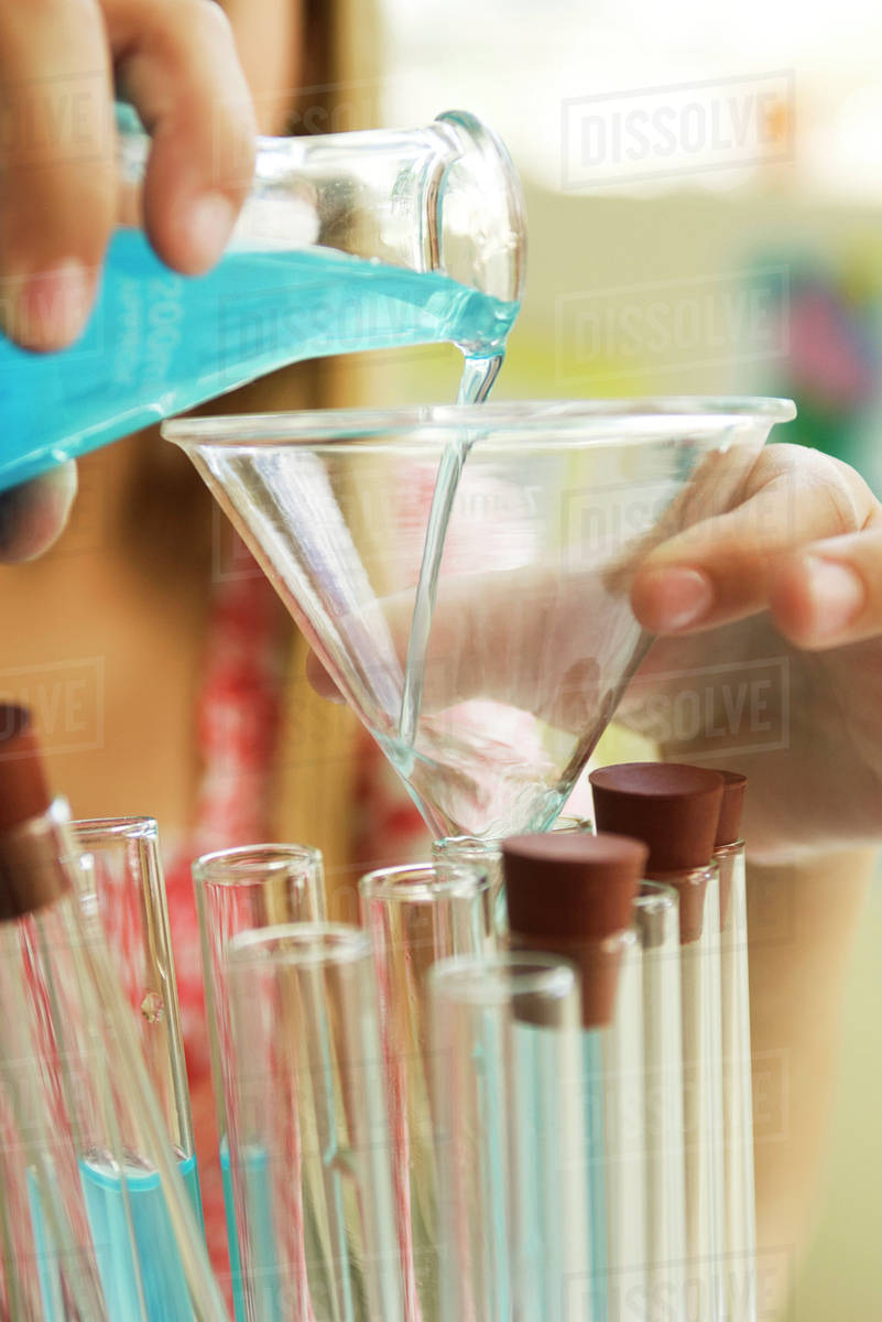 Elementary student transferring liquid from beaker to test tube using funnel, closeup Stock