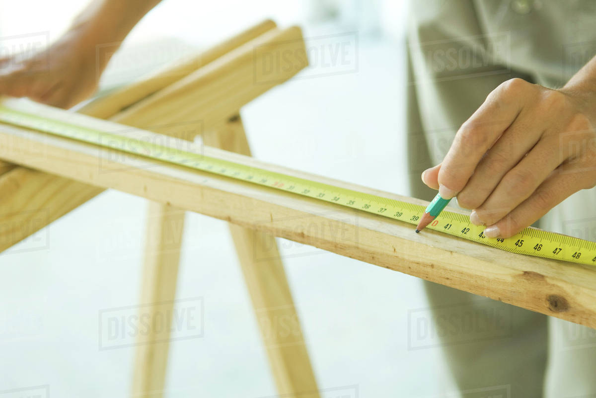 Unrecognizable person measuring wood with measuring tape Stock Photo