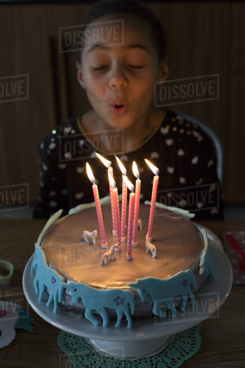 Girl blowing out candles on birthday cake Stock Photo Dissolve