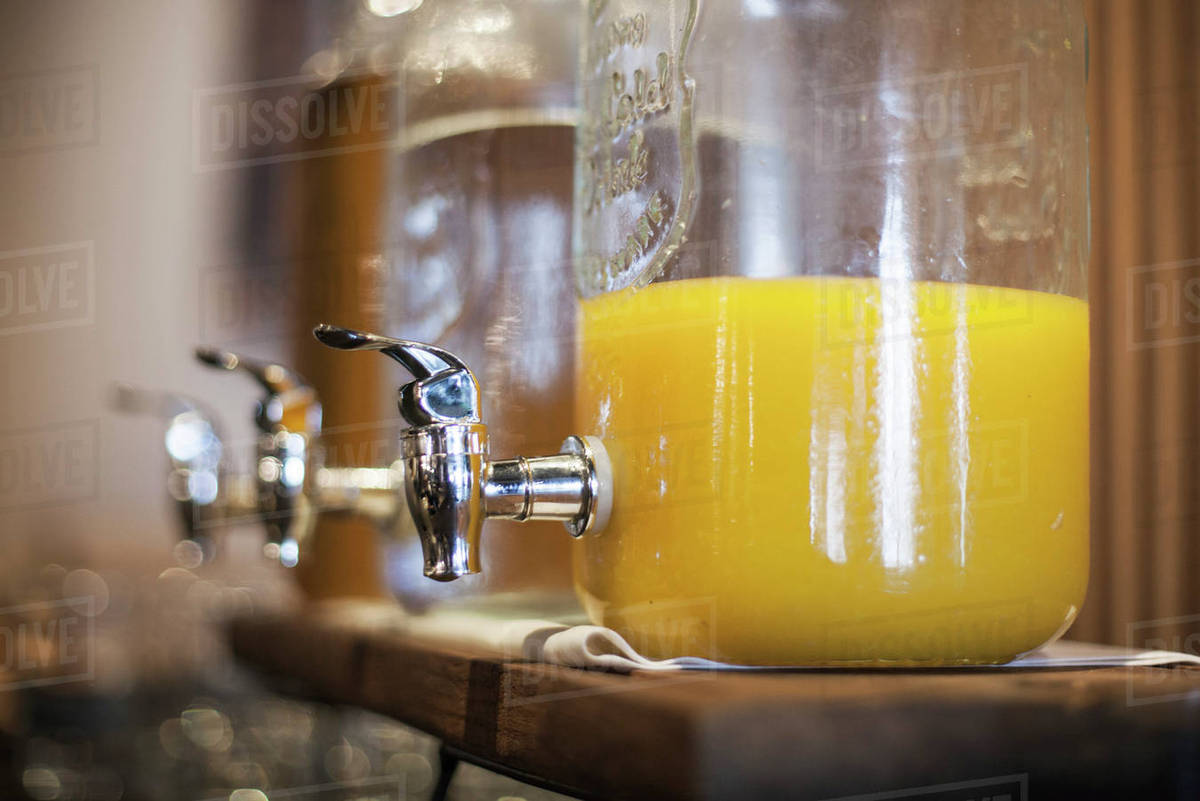 Orange juice in glass dispenser - Stock Photo - Dissolve