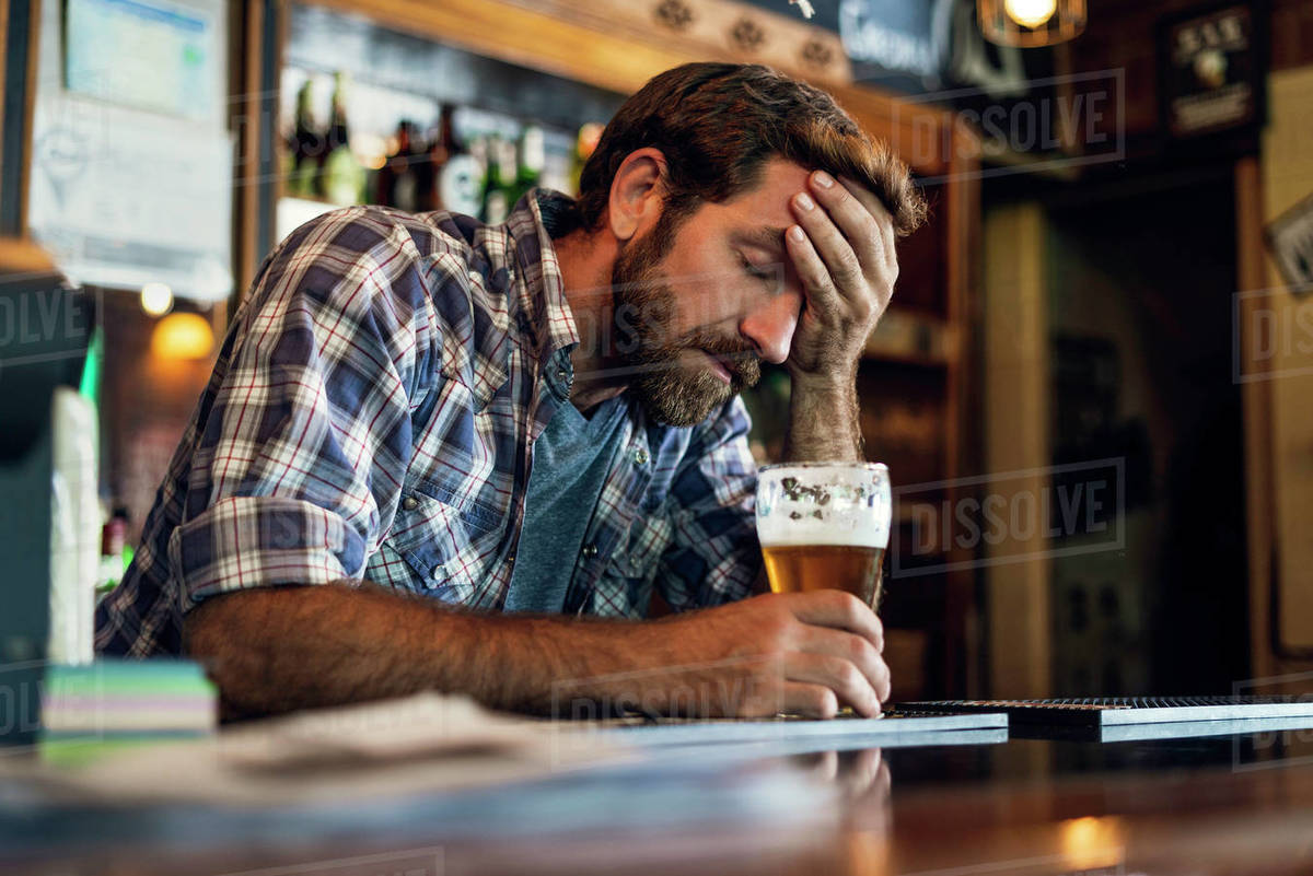 Sad man sitting in beer bar Stock Photo Dissolve