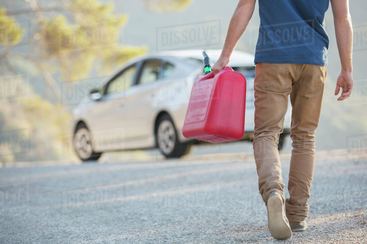 Man carrying gas can to car at roadside Stock Photo Dissolve