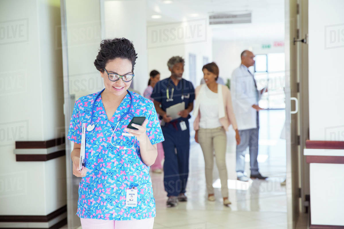 Nurse texting on cell phone in hospital corridor Stock Photo Dissolve
