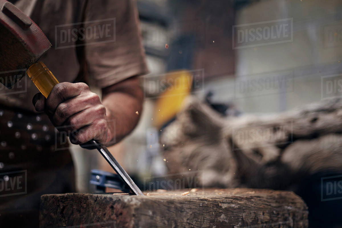 Blacksmith chiseling wood in Stock Photo Dissolve