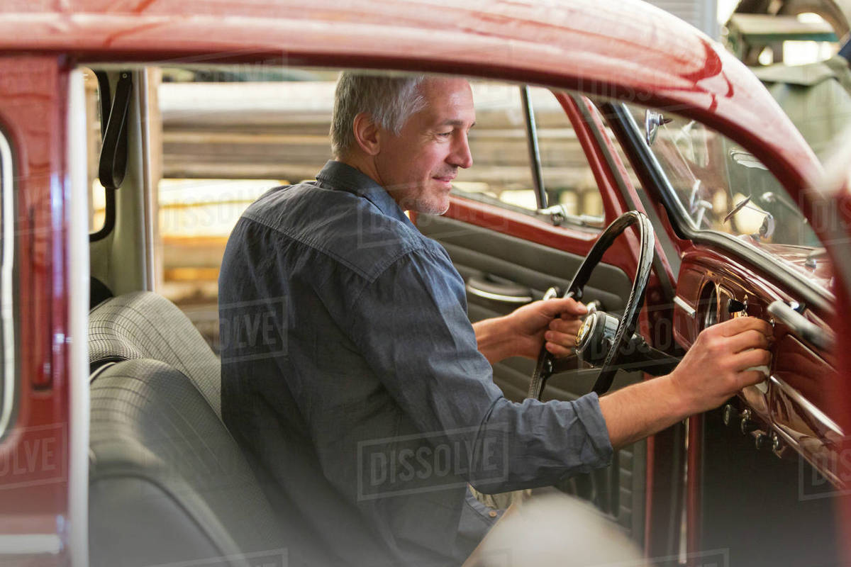 Mechanic inside classic car in auto repair shop Stock Photo Dissolve