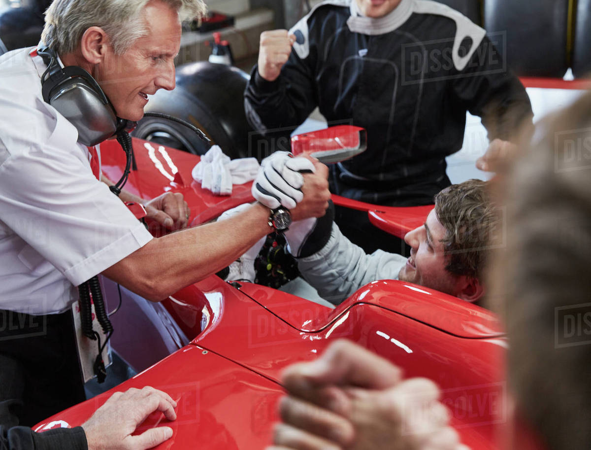 Manager and formula one race car driver handshaking, celebrating victory Royalty-free stock photo